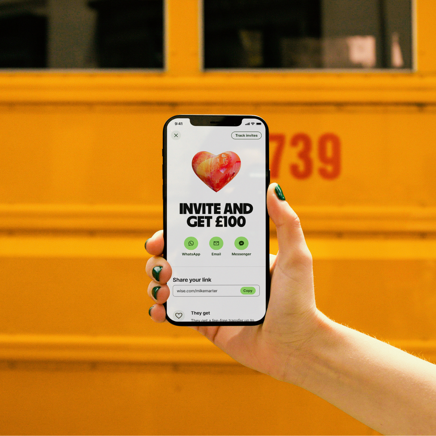 A phone held up against yellow bus.