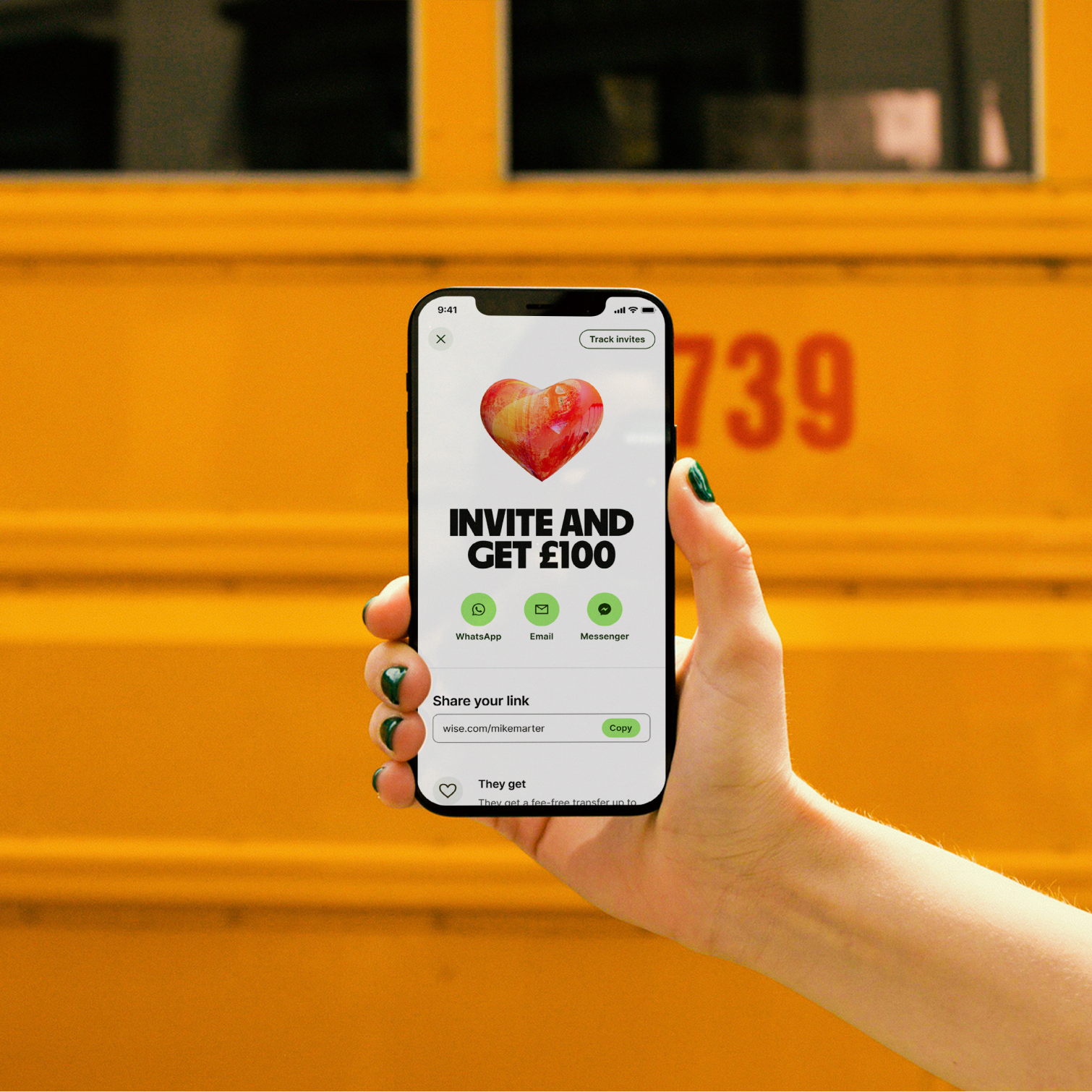 A phone held up against yellow bus.