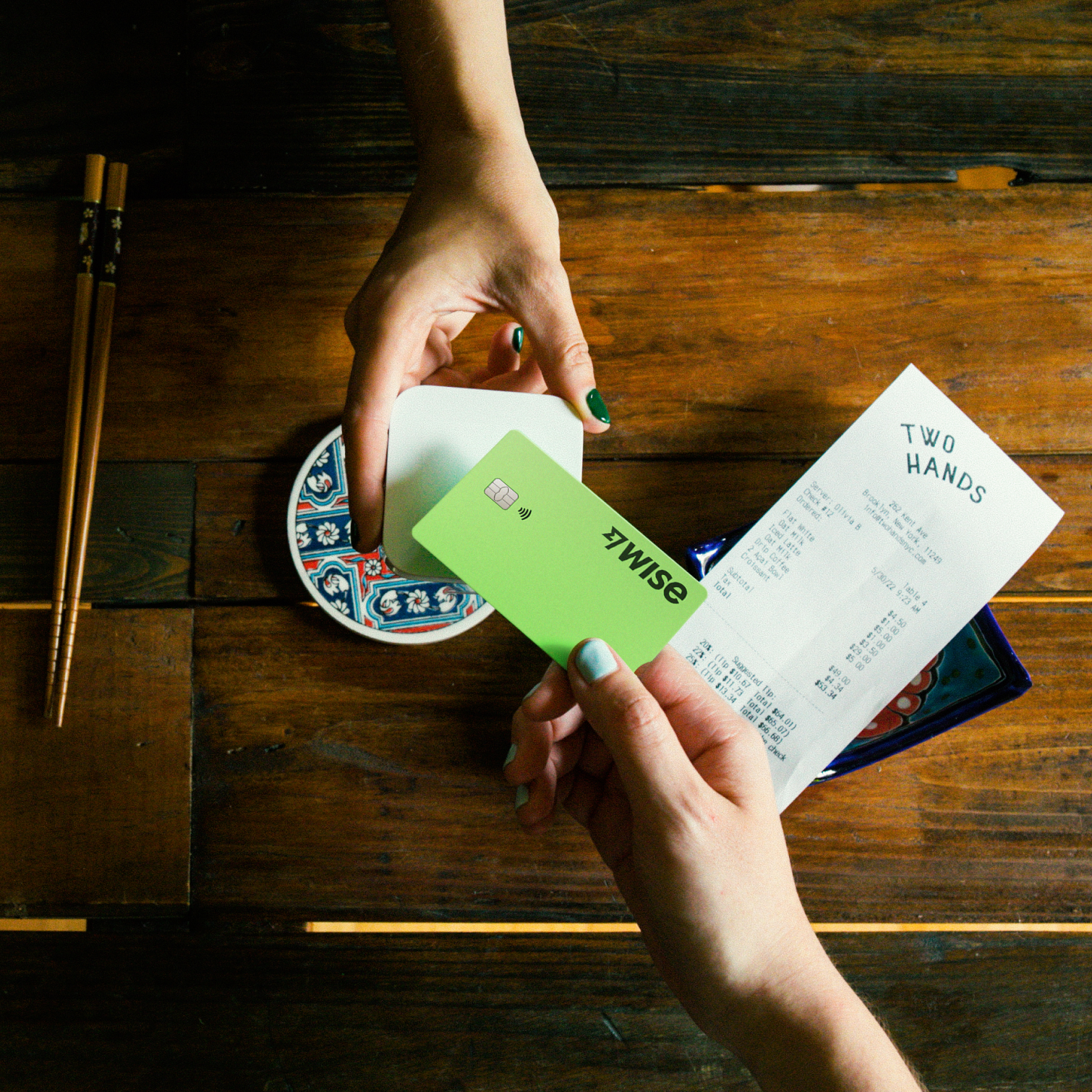 A shot from above, showing someone using the Wise card to pay for a restaurant bill.