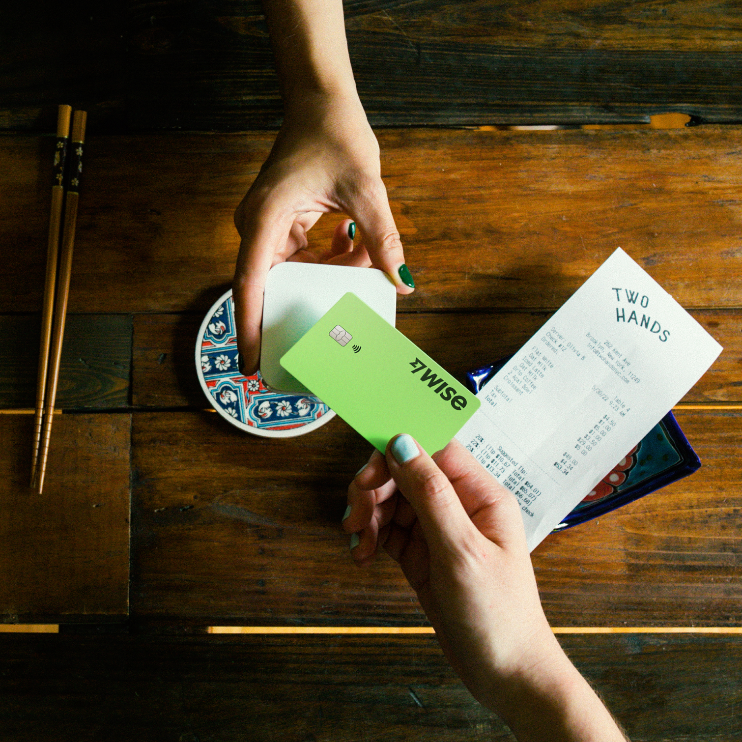 A shot from above, showing someone using the Wise card to pay for a restaurant bill.
