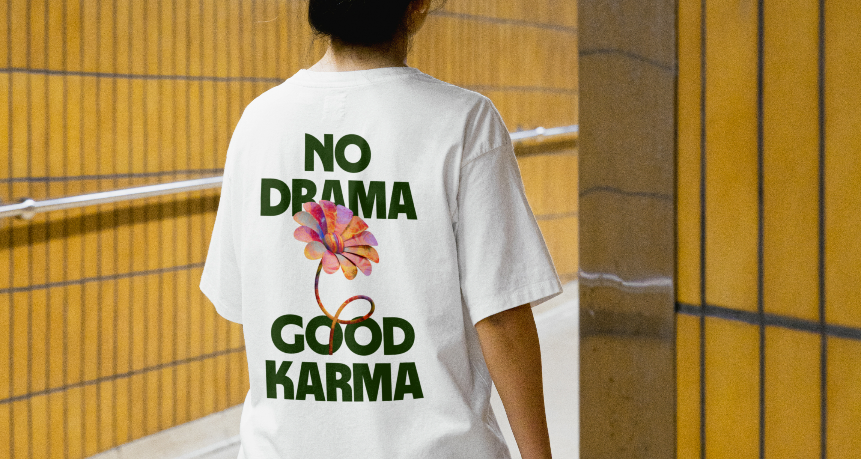 Woman wearing a Wise illustration t-shirt facing back in a train station